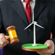 A man holds a windmill and a judge's gavel. A permit for the construction of wind turbines A man holds a windmill and a judge's gavel. A permit for the construction of wind turbines - PhotoDune Item for Sale