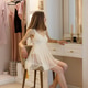 Young woman in dress sitting in front of mirror in fitting room at home in dressing room. Young woman in dress sitting in front of mirror in fitting room at home in dressing room. - PhotoDune Item for Sale