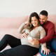 Expecting couple relaxing on couch using smartphone Expecting couple relaxing on couch using smartphone - PhotoDune Item for Sale