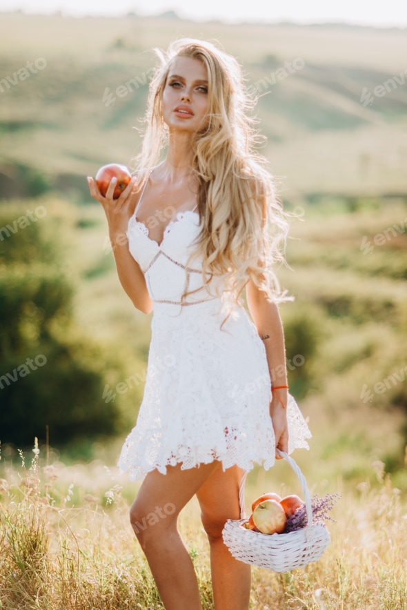 Beautiful sexy blonde girl in white dress posing in a field at sunset with a basket of fruit Stock Photo by Nikita_Karchevskyi Beautiful sexy blonde girl in white dress posing in a field at sunset with a basket of fruit Stock Photo by Nikita_Karchevskyi