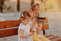 Sisters sitting in park on wooden bench with gadget tablet pad. Kids using technologies Sisters sitting in park on wooden bench with gadget tablet pad. Kids using technologies - PhotoDune Item for Sale