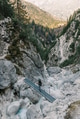 Woman standing on footbridge over mountain torrent, looking at landscape view Woman standing on footbridge over mountain torrent, looking at landscape view - PhotoDune Item for Sale
