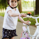 A girl in a helmet with a bicycle walks along a path in a park. A girl in a helmet with a bicycle walks along a path in a park. - PhotoDune Item for Sale
