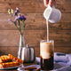 Women's hand with creamer pouring milk in glass with coffee Women's hand with creamer pouring milk in glass with coffee - PhotoDune Item for Sale