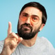 Serious man pointing finger wearing sunglasses on blue background Serious man pointing finger wearing sunglasses on blue background - PhotoDune Item for Sale