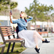 Young cute blond girl with short hair and bright pink lips sitting on a wooden bench making a selfie Young cute blond girl with short hair and bright pink lips sitting on a wooden bench making a selfie - PhotoDune Item for Sale
