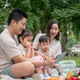 Asian parents are taking their kids on a picnic in a green park, watching a cartoon on a tablet. Asian parents are taking their kids on a picnic in a green park, watching a cartoon on a tablet. - PhotoDune Item for Sale