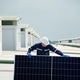 Worker installs solar panel on a rooftop during daylight hours in an urban area Worker installs solar panel on a rooftop during daylight hours in an urban area - PhotoDune Item for Sale