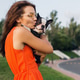 young happy smiling woman in orange dress having fun playing with dog in park young happy smiling woman in orange dress having fun playing with dog in park - PhotoDune Item for Sale