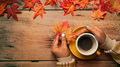 Woman in warm sweater holding a white cup of hot coffee and maple leaves on wooden table. Woman in warm sweater holding a white cup of hot coffee and maple leaves on wooden table. - PhotoDune Item for Sale