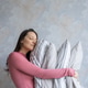 woman holds pile of pillows in her hands. pillows are in different colors, look like stack. woman holds pile of pillows in her hands. pillows are in different colors, look like stack. - PhotoDune Item for Sale