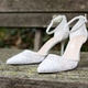 White wedding shoes with lace and heel on old wooden boards White wedding shoes with lace and heel on old wooden boards - PhotoDune Item for Sale