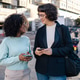Two friends using smartphone in the street Two friends using smartphone in the street - PhotoDune Item for Sale