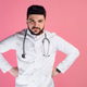 Brunette male doctor, intern standing, holding hands on sides, looking at camera. Brunette male doctor, intern standing, holding hands on sides, looking at camera. - PhotoDune Item for Sale