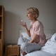 Positive thoughtful woman sitting in bed, smiling holding glass of water and planning new day. Positive thoughtful woman sitting in bed, smiling holding glass of water and planning new day. - PhotoDune Item for Sale