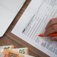 Close-up of a person filling out a 1040 tax form with an orange pen next to a laptop. Tax season Close-up of a person filling out a 1040 tax form with an orange pen next to a laptop. Tax season - PhotoDune Item for Sale