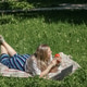 A blonde woman lies on the green grass with a laptop, surfing the internet in a city park A blonde woman lies on the green grass with a laptop, surfing the internet in a city park - PhotoDune Item for Sale