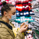 Woman in face mask selects beads products in a handicraft store. Shopping for hobbies and creativity Woman in face mask selects beads products in a handicraft store. Shopping for hobbies and creativity - PhotoDune Item for Sale