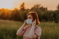Young redhead woman puting on face mask walking at sunset in summer field. Scenic landscape Young redhead woman puting on face mask walking at sunset in summer field. Scenic landscape - PhotoDune Item for Sale
