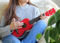Latino woman enjoys playing a red ukulele during a relaxing time at home. Latino woman enjoys playing a red ukulele during a relaxing time at home. - PhotoDune Item for Sale