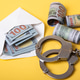 Handcuffs and cash representing crime and corruption Handcuffs and cash representing crime and corruption - PhotoDune Item for Sale