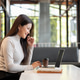 Happy asian woman looking and typing on laptop aside books and coffee while sitting at table in cafe Happy asian woman looking and typing on laptop aside books and coffee while sitting at table in cafe - PhotoDune Item for Sale