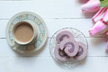 A cup of milk coffee served with Taro Swiss roll cake on white wooden table A cup of milk coffee served with Taro Swiss roll cake on white wooden table - PhotoDune Item for Sale