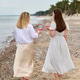 Two young women enjoying pink wine on serene beach picnic by sea Two young women enjoying pink wine on serene beach picnic by sea - PhotoDune Item for Sale