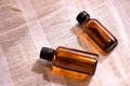 Amber glass bottle of essential oil placed on soft textured fabric Amber glass bottle of essential oil placed on soft textured fabric - PhotoDune Item for Sale