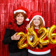 Happy friends in a santa costume holding golden balloons with the shape 2026 on a red background. Happy friends in a santa costume holding golden balloons with the shape 2026 on a red background. - PhotoDune Item for Sale