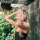 A beautiful blonde woman in a swimsuit takes a cool shower at a tropical resort. A beautiful blonde woman in a swimsuit takes a cool shower at a tropical resort. - PhotoDune Item for Sale