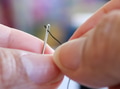 Closeup of person threading a needle with black thread. Closeup of person threading a needle with black thread. - PhotoDune Item for Sale