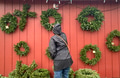Woman wearing a rain coat at the Christmas tree shop, choosing natural Christmas wreaths for home Woman wearing a rain coat at the Christmas tree shop, choosing natural Christmas wreaths for home - PhotoDune Item for Sale