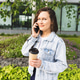 Woman Enjoying Coffee Outdoors Talking on Phone in Urban Green Space Woman Enjoying Coffee Outdoors Talking on Phone in Urban Green Space - PhotoDune Item for Sale