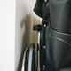Close up of part of a black wheelchair sitting in a corner against a wall Close up of part of a black wheelchair sitting in a corner against a wall - PhotoDune Item for Sale