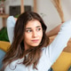 Young woman stretching her arms sitting on the sofa at home. Young woman stretching her arms sitting on the sofa at home. - PhotoDune Item for Sale