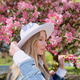 A beautiful young woman a hat near a cherry blossom tree A beautiful young woman a hat near a cherry blossom tree - PhotoDune Item for Sale