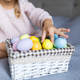 Young girl reaching for colorful eggs in a basket while sitting on a bed Young girl reaching for colorful eggs in a basket while sitting on a bed - PhotoDune Item for Sale