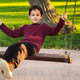 A young boy with brown hair sits on a wooden swing in a park. A young boy with brown hair sits on a wooden swing in a park. - PhotoDune Item for Sale