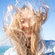 Happy woman with tousled messy long blond hair against clear blue sky Happy woman with tousled messy long blond hair against clear blue sky - PhotoDune Item for Sale
