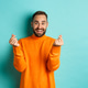 Smiling handsome man showing hearts and looking happy, lucky gesture, standing in orange sweater Smiling handsome man showing hearts and looking happy, lucky gesture, standing in orange sweater - PhotoDune Item for Sale