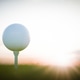 Golf ball on tee at sunset awaits the perfect drive Golf ball on tee at sunset awaits the perfect drive - PhotoDune Item for Sale