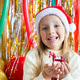 Smiling young girl in Santa hat holding holiday figurine at festive party Smiling young girl in Santa hat holding holiday figurine at festive party - PhotoDune Item for Sale