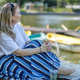 A blonde woman drinks iced tea in a park by a lake. Summer, outdoor recreation. A blonde woman drinks iced tea in a park by a lake. Summer, outdoor recreation. - PhotoDune Item for Sale