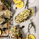 Top view Giant Fresh Pacific Oysters on a light background. Lemon and oregano. Selective focus. Top view Giant Fresh Pacific Oysters on a light background. Lemon and oregano. Selective focus. - PhotoDune Item for Sale