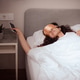 woman takes phone from bedside table woman takes phone from bedside table - PhotoDune Item for Sale