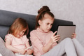 Two little girls sisters sitting in bedroom, holding gadgets. Kids using technologies at home Two little girls sisters sitting in bedroom, holding gadgets. Kids using technologies at home - PhotoDune Item for Sale