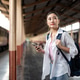Asian woman holding phone and backpack strap looking ahead while standing waiting at train station. Asian woman holding phone and backpack strap looking ahead while standing waiting at train station. - PhotoDune Item for Sale