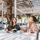 Two female friends are laughing in a summer cafe. Two female friends are laughing in a summer cafe. - PhotoDune Item for Sale