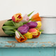 Bouquet of colorful tulips in craft paper on a wooden surface with a white mug in the background Bouquet of colorful tulips in craft paper on a wooden surface with a white mug in the background - PhotoDune Item for Sale